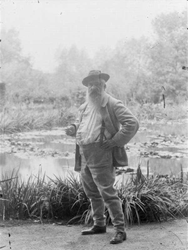 Claude Monet standing in front of his water lily pond